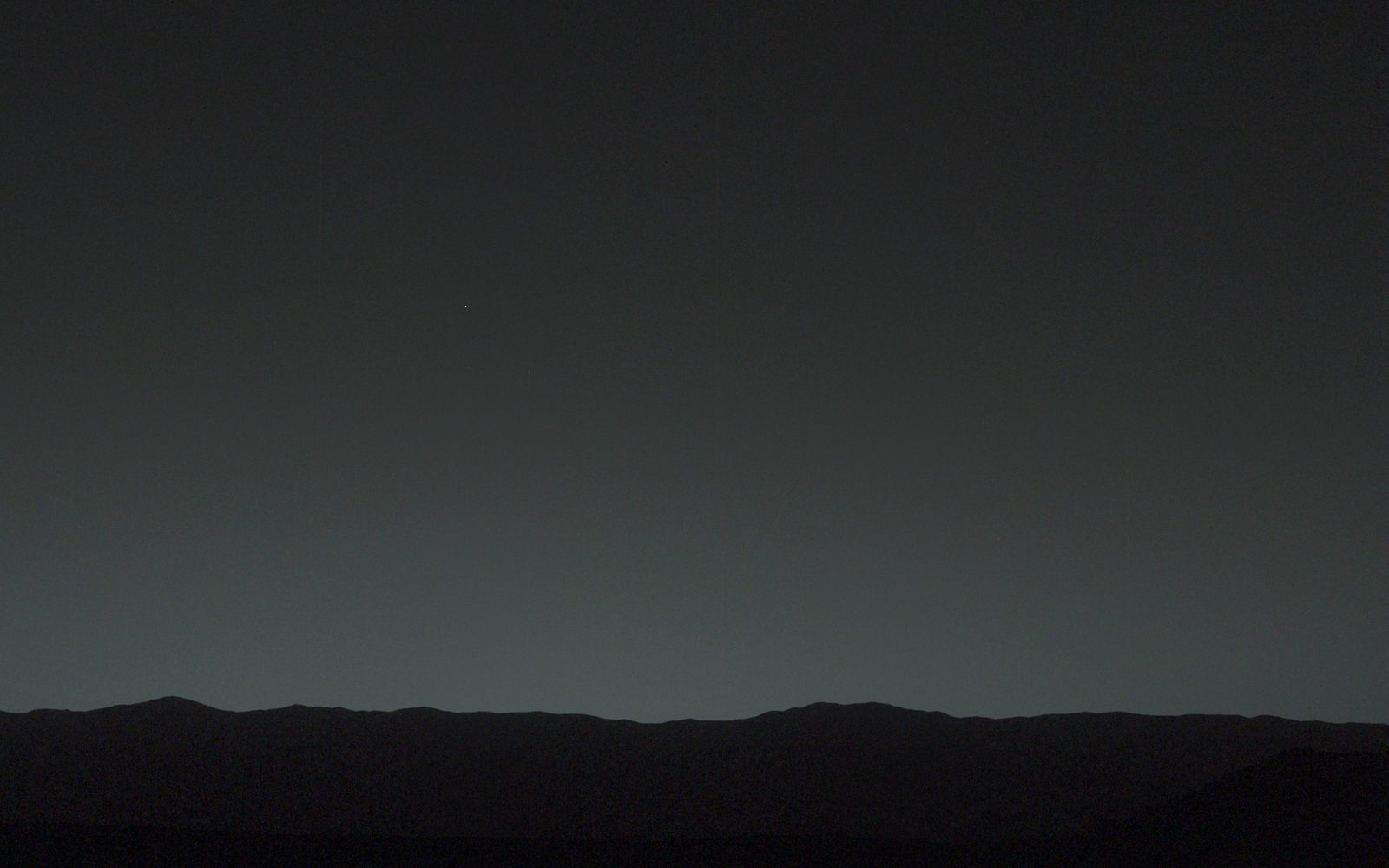 Un cielo gris de anochecer sobre una línea de colinas oscuras; la Tierra y la Luna son dos puntos diminutos sobre el horizonte.
