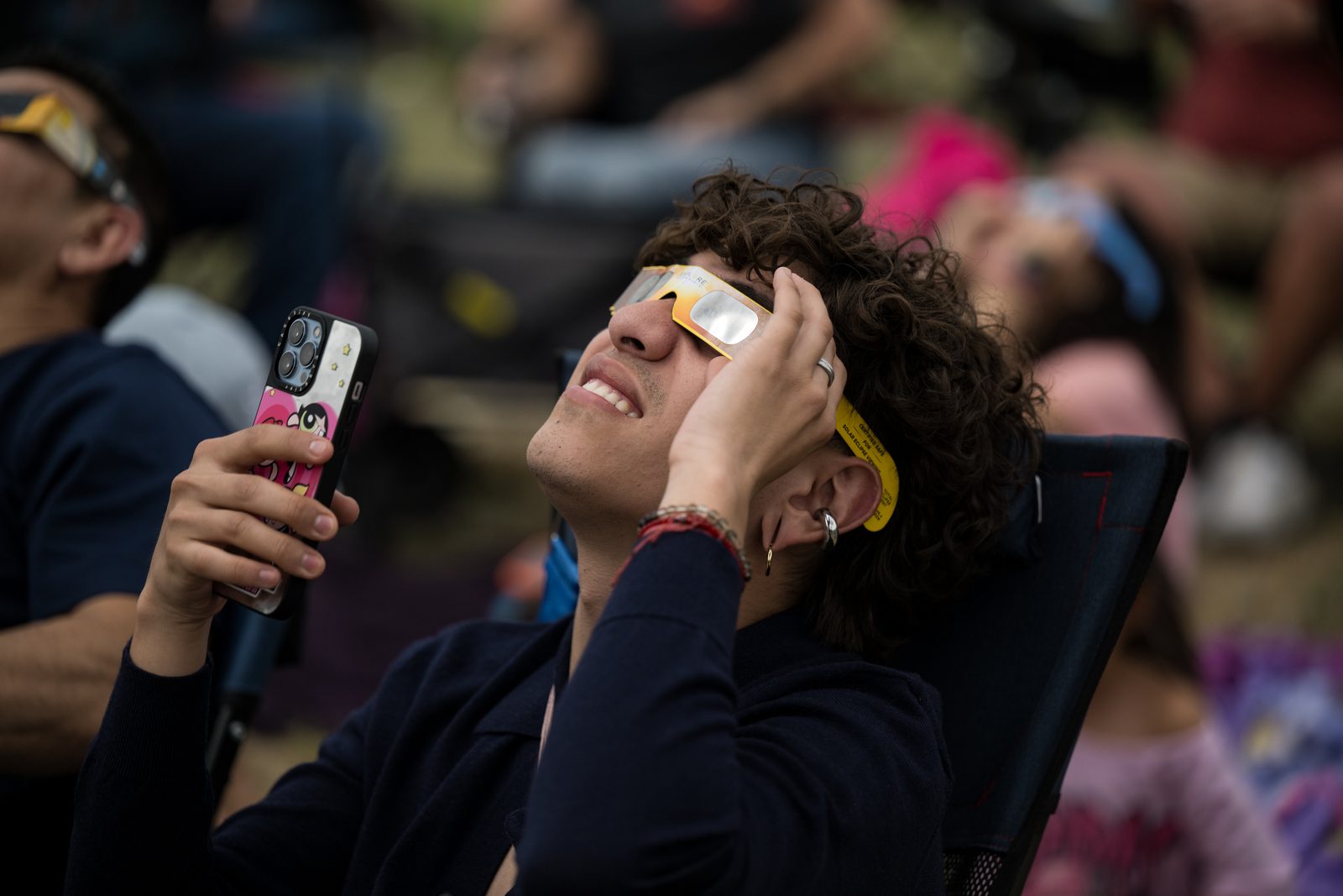 Un grupo de personas mira hacia arriba con filtros oscuros de cartón puestos sobre los ojos.