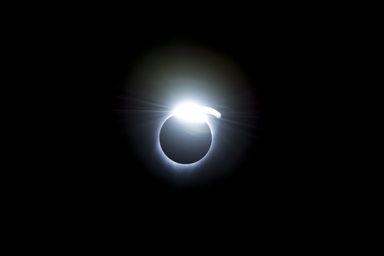 Un anillo delgado de luz con un punto cegador en un extremo, sobre fondo negro.
