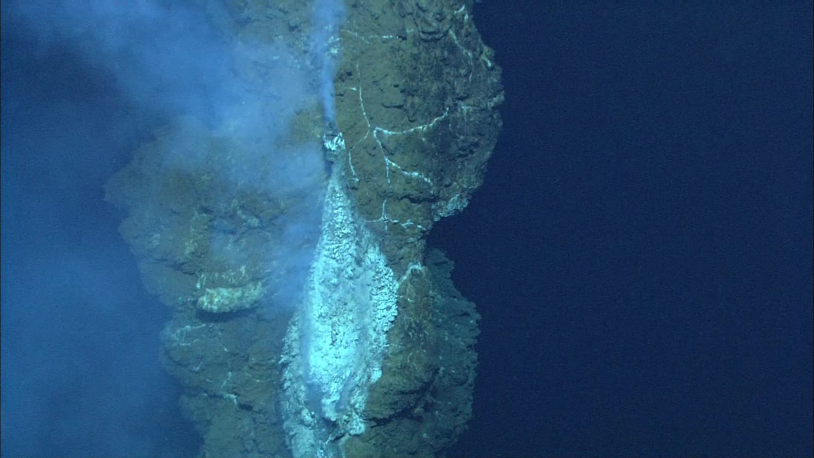 Una chimenea de roca en el fondo del mar expulsa una columna de agua negra e hirviendo en la oscuridad.