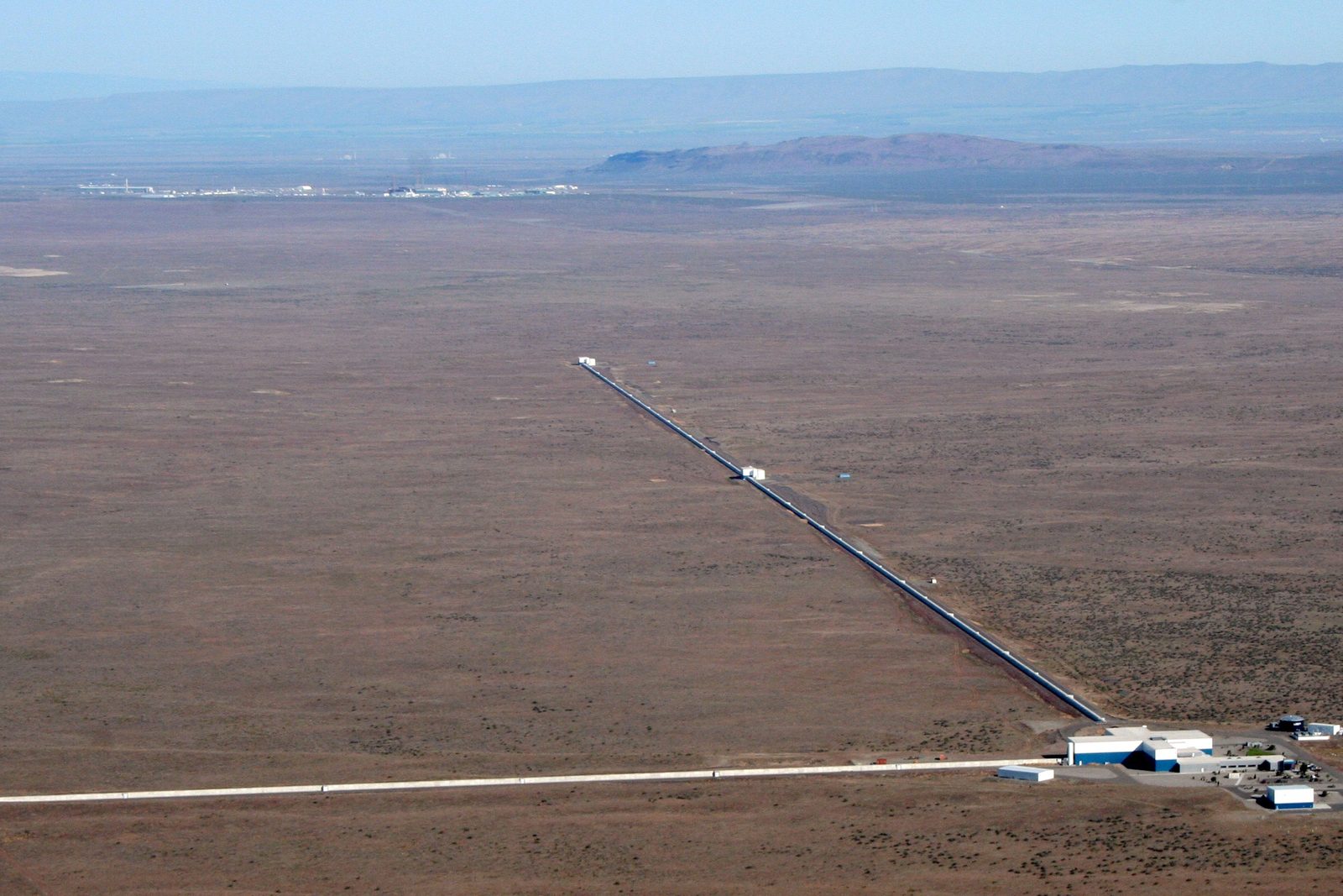 Vista aérea de un observatorio en pleno desierto: dos túneles rectos y larguísimos salen de un edificio central en forma de L, uno se ve entero y el otro se pierde fuera del encuadre.