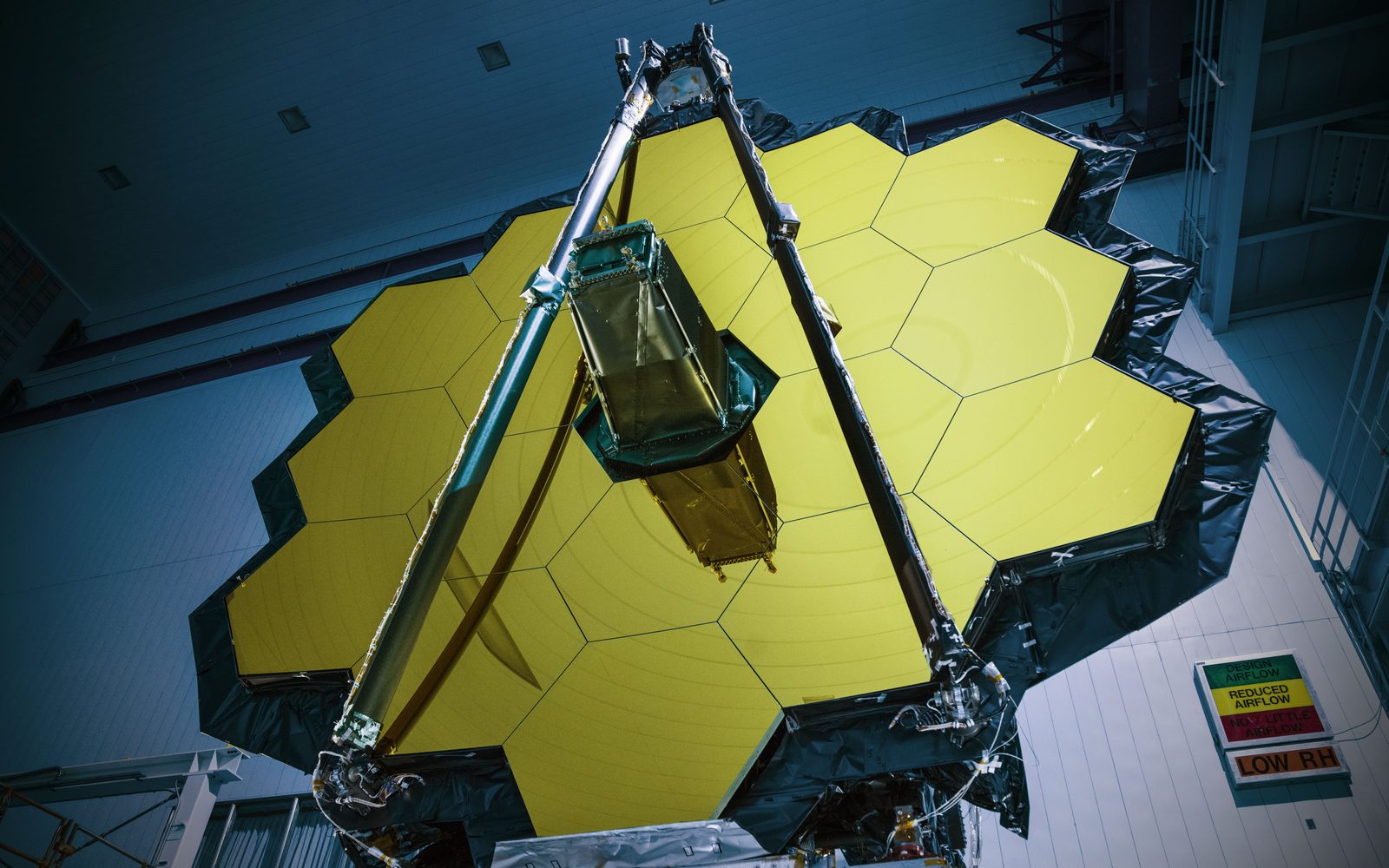 El espejo dorado del telescopio espacial James Webb, completamente desplegado, ocupa una sala limpia de techo altísimo con técnicos de blanco a sus pies.