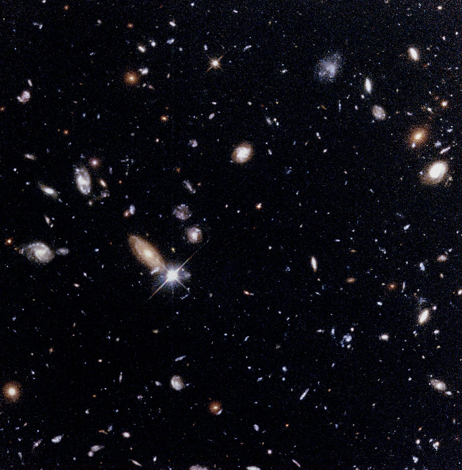 Un fondo negro sembrado de cientos de manchas de luz: galaxias espirales, elípticas y diminutas motas rojizas y azuladas.