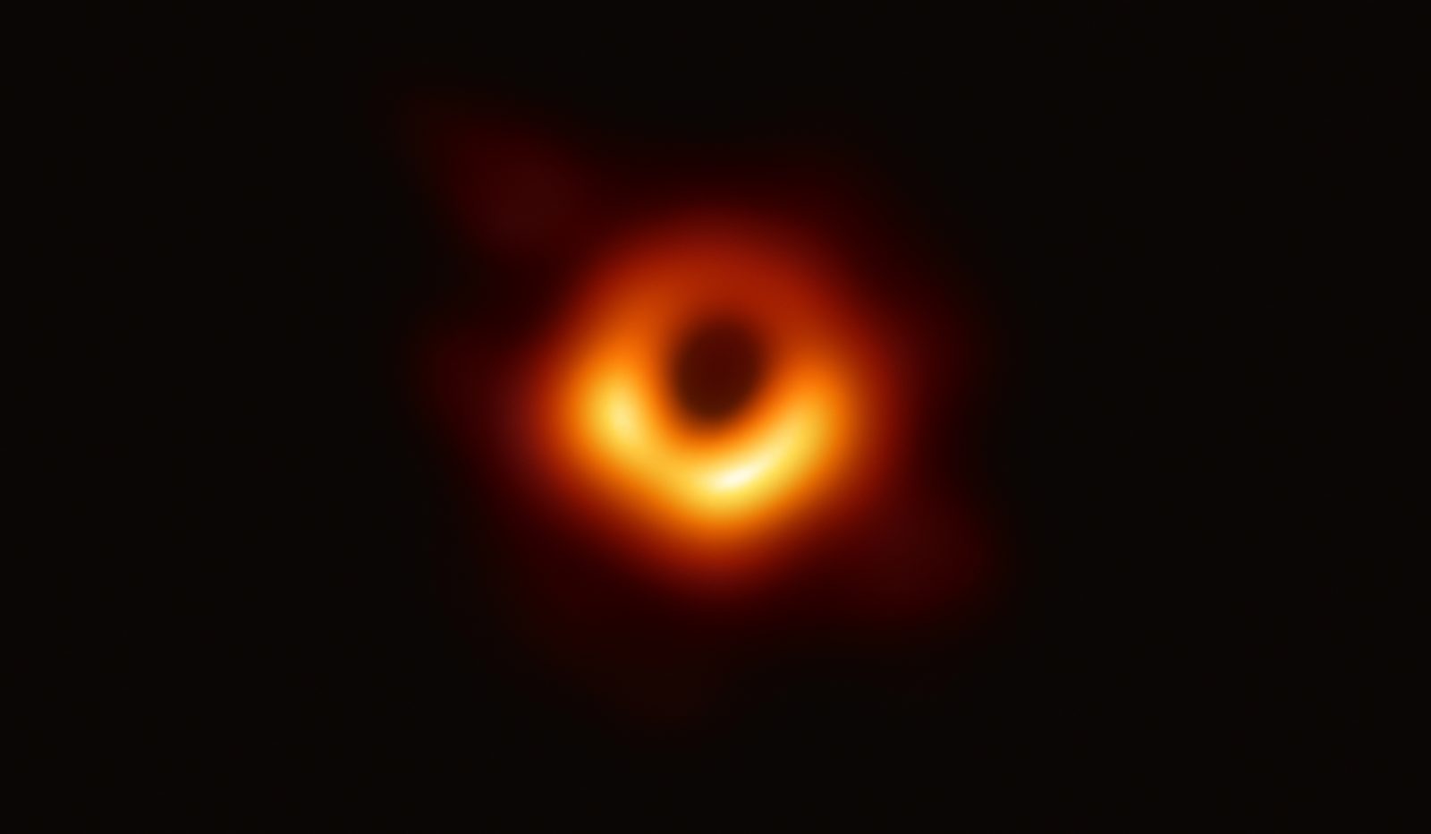 Un anillo naranja y desigual de luz alrededor de una zona central completamente oscura, sobre fondo negro.