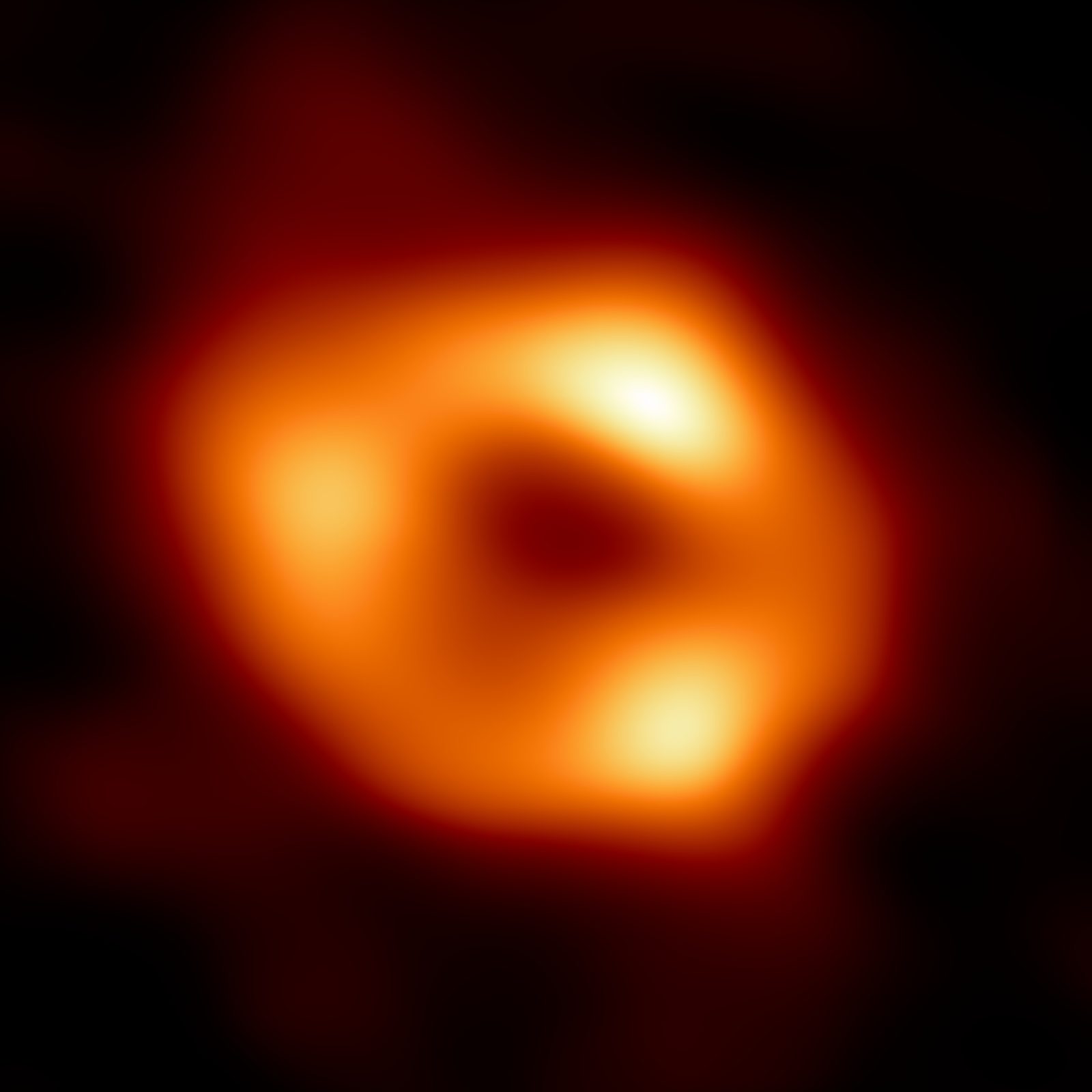 Un anillo naranja difuso de gas brillante rodeando una región central oscura.