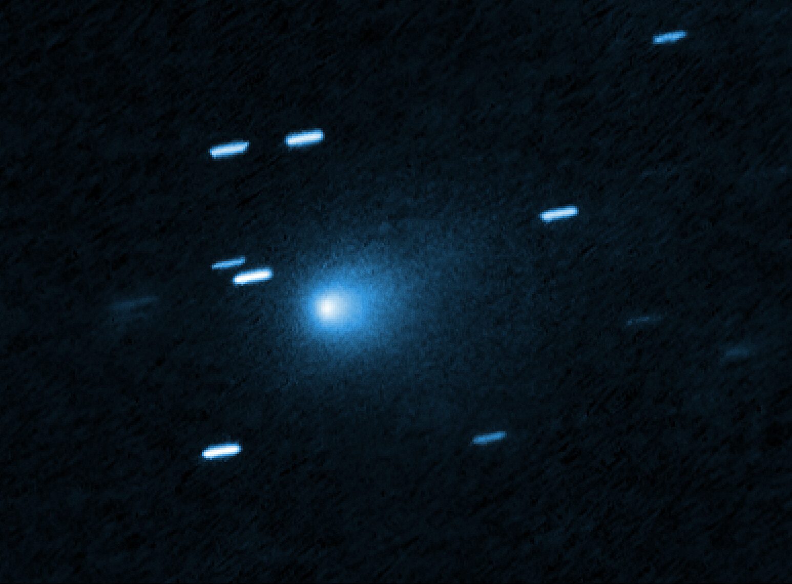 Sobre un fondo azul oscuro, una mancha luminosa y difusa en el centro, rodeada de estrellas convertidas en rayas cortas y paralelas.