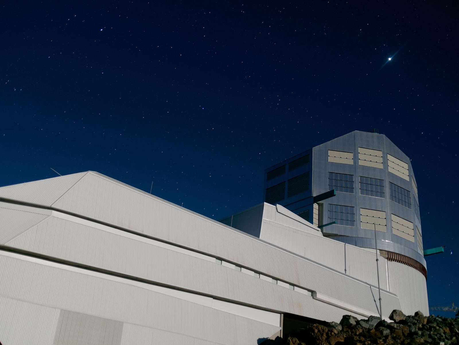El edificio del observatorio abierto de noche en la cima de un cerro, bajo un cielo cuajado de estrellas.