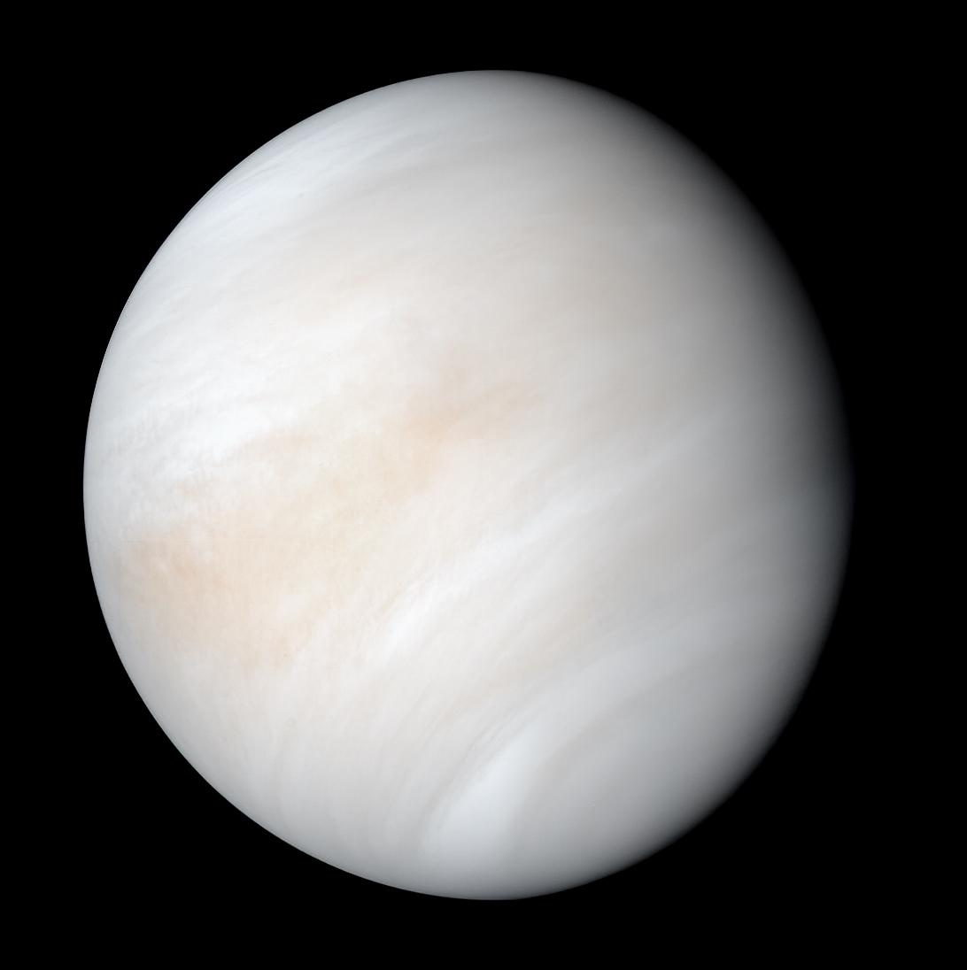 El disco de Venus cubierto por entero de nubes blancas y crema con vetas anaranjadas, sobre fondo negro.