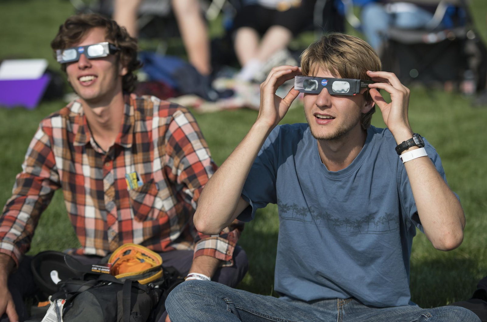 Un grupo de personas mirando hacia arriba con lentes de eclipse de cartón puestos.