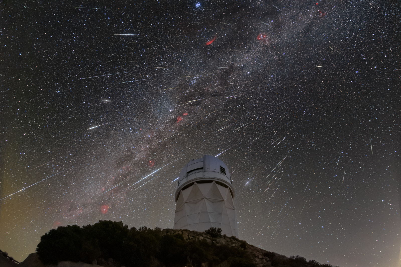 Meteoros cruzando el cielo sobre la cúpula del telescopio Mayall de cuatro metros, con el brazo polvoriento de la Vía Láctea arqueado sobre ellos.